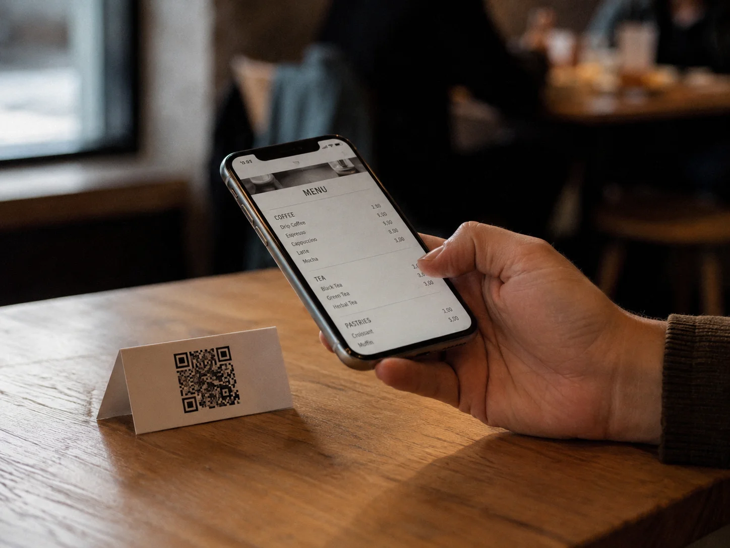 A person scanning a QR code on a printed café table card with a phone, the redirect resolving normally with no upgrade prompt