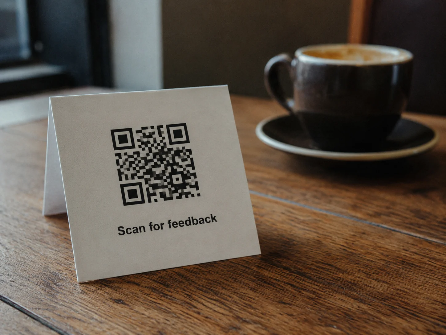 Printed QR code on a cafe table card with 'Scan for feedback' text — real-world Google Forms QR code placement example